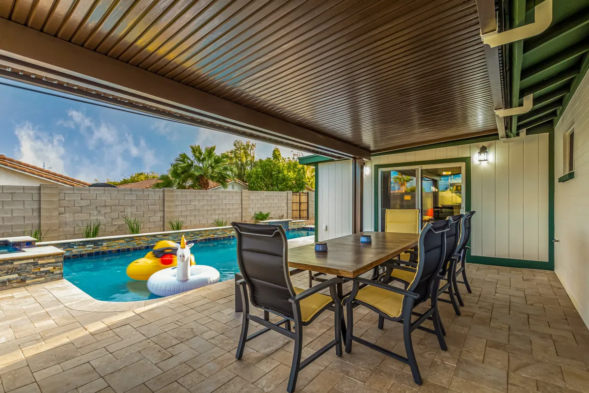 This exterior image captures a dining table set next to a swimming pool, with colorful floaties in the water. The scene evokes lively outdoor dining experiences, playful poolside afternoons, and the joy of sharing meals and laughter with friends in a vibrant setting.