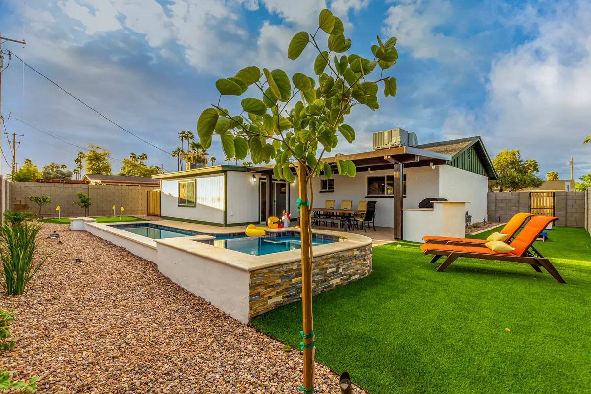 This image features a sparkling swimming pool surrounded by lounge chairs and a patio area, set under a clear sky. The setting encourages sunbathing, swimming, and outdoor dining, perfect for social gatherings with friends or family. The relaxed and cheerful mood is accentuated by the inviting layout and sunset ambiance.